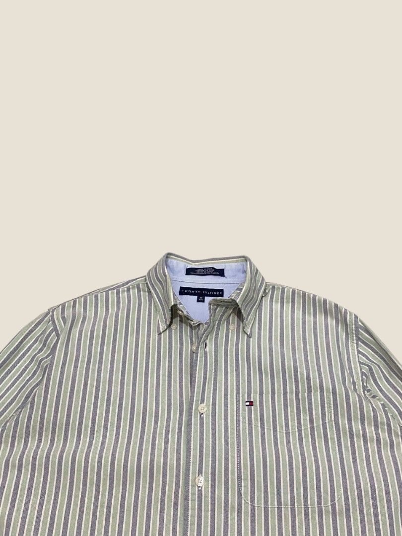 Vintage Tommy Hilfiger Multi-Striped Button-Down Shirt (Category: Formal Shirts) located in Santa Rosa. Submitted by revive.n.thrive (Listing ID 1463303901, Image 3). Description: A refined, high-grade vintage essential. Features an elegant muted green, navy, and cream vertical stripe pattern constructed from a premium, soft-touch cotton weave. Embodying an effortless preppy vibe and a quiet luxury aesthetic, this piece is finished with a sharp b
