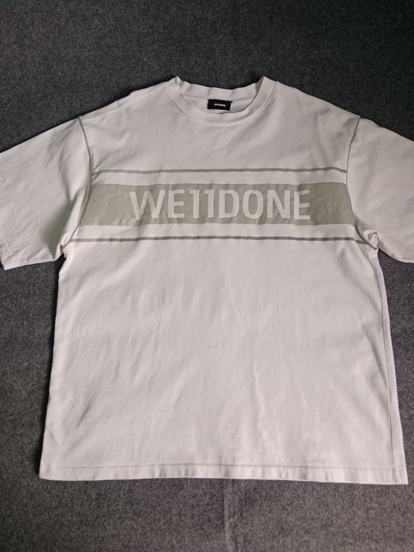 WE11DONE White Graphic T-Shirt Size S (Category: Tshirts & Polo Shirts ) located in Alburquerque. Submitted by romnickhatosa (Listing ID 1463176787, Image 1). Description: - Brand: WE11DONE - Color: White - Design: Grey graphic stripe across chest with brand name - Size: S - Material: 100% Cotton - Origin: Made in Korea - Style: Great for casual wear.
