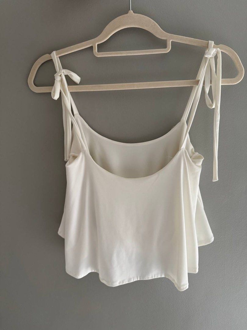 White Tie Shoulder Tank Top (Category: Sleeveless) located in Taguig. Submitted by anxmz (Listing ID 1463145029, Image 1). Description: - Cute white tank top - Adjustable tie shoulder straps - Soft, drapey fabric - Relaxed fit with a flowy hem - Versatile for dressing up or down - Ideal for summer wear or layering.