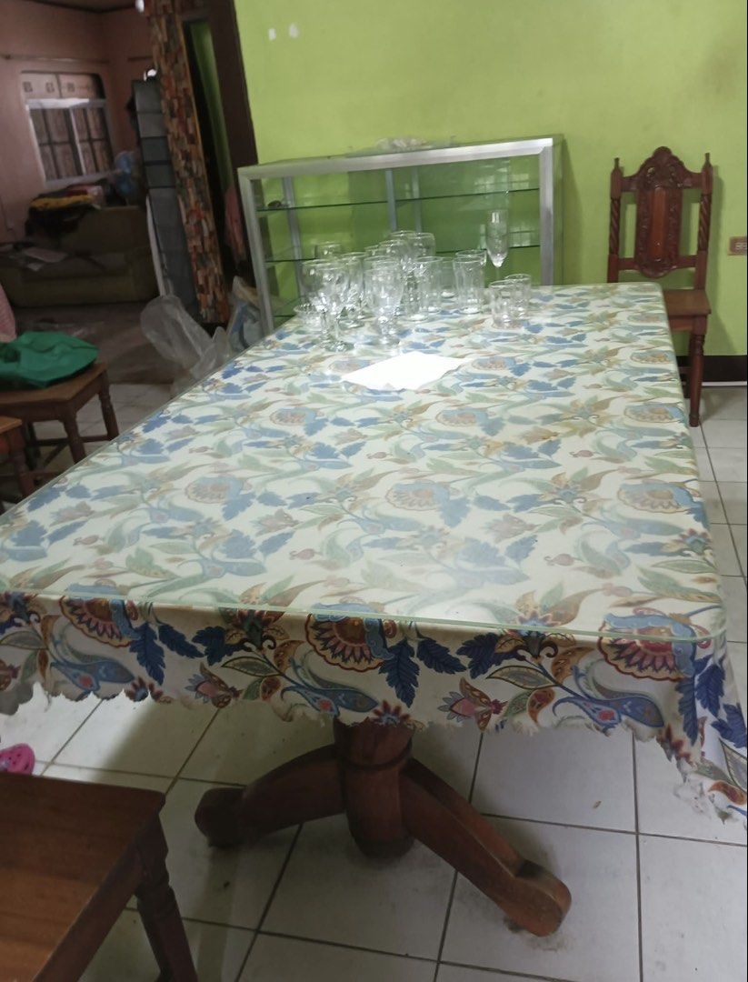 Wooden Table (Category: Tables & Sets) located in Tanauan. Submitted by liltobysbakes (Listing ID 1463133817, Image 1). Description: - Sturdy wooden pedestal dining table - Comes with a lovely blue and green floral tablecloth - Great size for family meals and gatherings - Glasses shown in photos are not included - Ready for its new home.