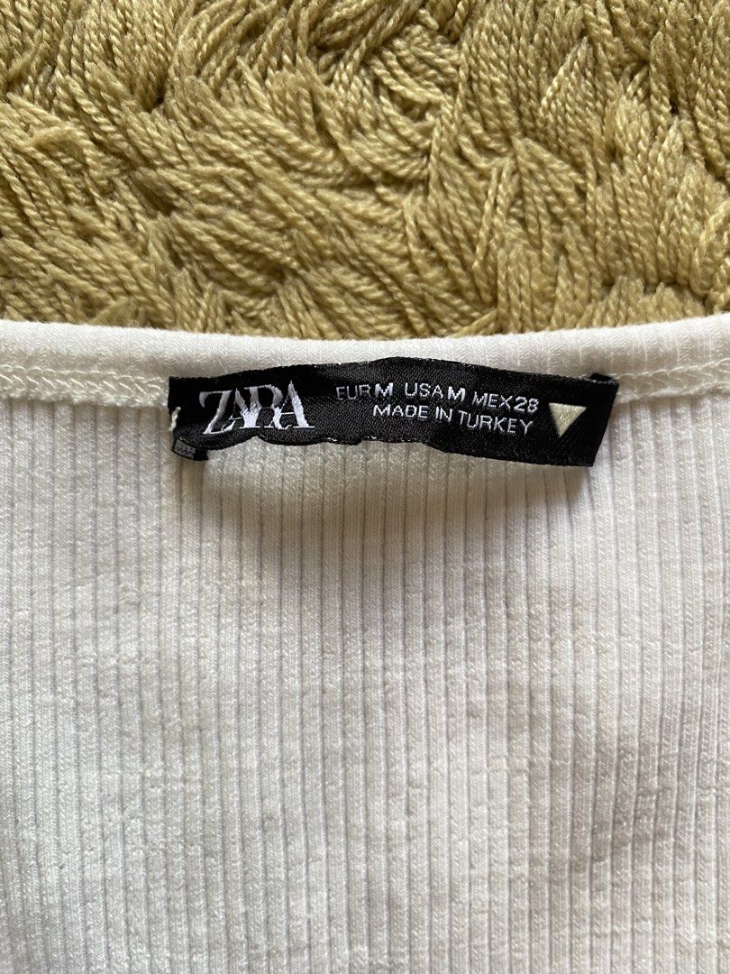 Zara Ribbed Tank Top White (Category: Sleeveless) located in Amadeo. Submitted by selectsbysam (Listing ID 1463124021, Image 3). Description: - Basic white ribbed tank top from Zara - Features a stylish square neckline - Sleeveless design for comfort and ease - Ideal for layering or wearing as a standalone piece - Incredibly comfortable and versatile - Effortlessly pairs with any outfit in your closet.