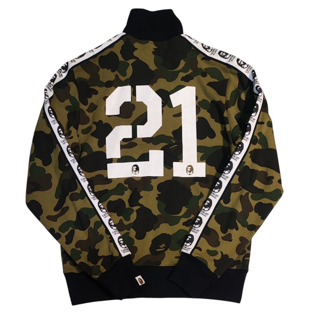 A Bathing Ape BAPE 21 Camo Track Jacket (Category: Coats, Jackets and Outerwear) located in Quezon City. Submitted by selectedandlegitgoods (Listing ID 1463539942, Image 2). Description: - Classic BAPE camo cotton track jacket - Iconic ape head logo on front - Large '21' graphic on back - Ape head tape detailing down sleeves - Ribbed collar, cuffs, and hem - Essential for any streetwear collection.