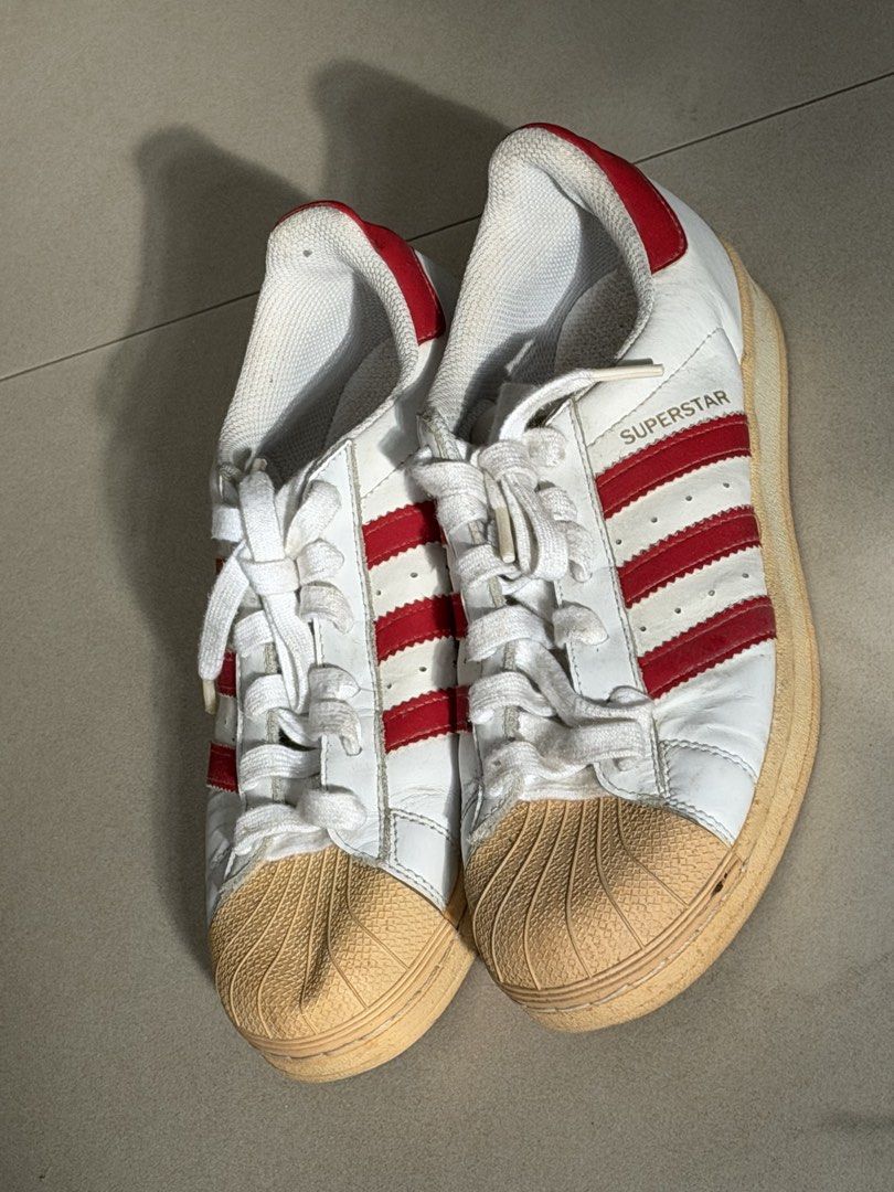 Adidas Superstar White Red Stripes Shell Toe Sneakers (Category: Sneakers) located in Taguig. Submitted by anxmz (Listing ID 1463407819, Image 2). Description: - Classic Adidas Superstar sneakers - White with iconic red stripes - Features the signature shell toe - White laces - Soles have some wear but good grip remaining - Perfect for everyday wear - Essential addition to any sneaker collection.