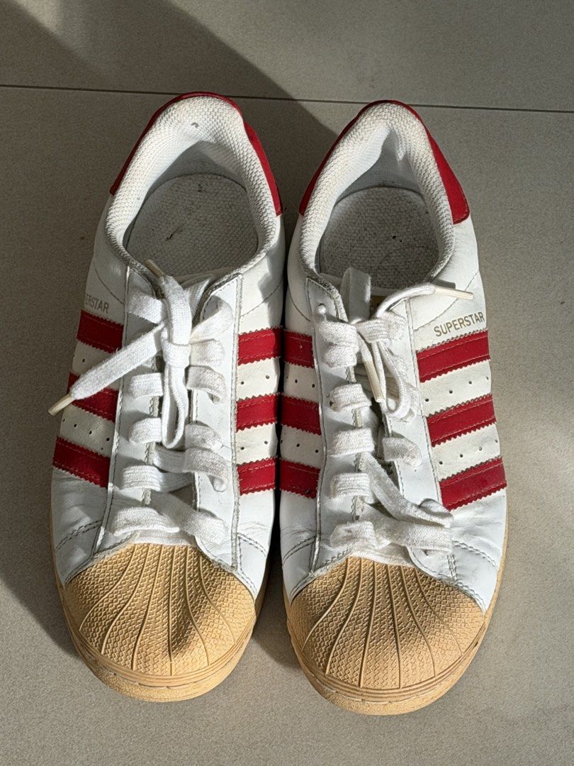 Adidas Superstar White Red Stripes Shell Toe Sneakers (Category: Sneakers) located in Taguig. Submitted by anxmz (Listing ID 1463407819, Image 1). Description: - Classic Adidas Superstar sneakers - White with iconic red stripes - Features the signature shell toe - White laces - Soles have some wear but good grip remaining - Perfect for everyday wear - Essential addition to any sneaker collection.