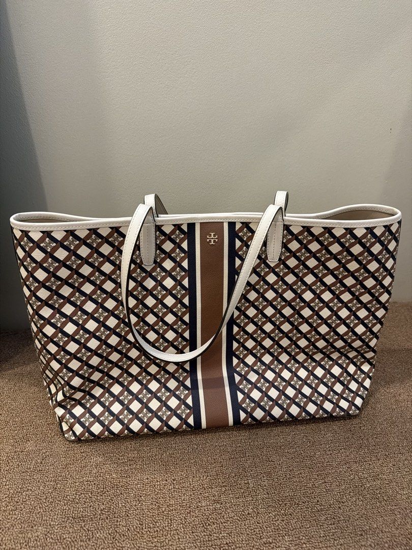Authentic Tory Burch Tote Bag (Category: Luxury Bags & Wallets) located in Quezon City. Submitted by purpleblush (Listing ID 1463344544, Image 1). Description: - Classic Tory Burch tote bag - Signature logo print in brown, navy, and white - White leather trim and handles - Interior: snap closure pocket and large central compartment - Ideal for everyday use or travel - Spacious interior.