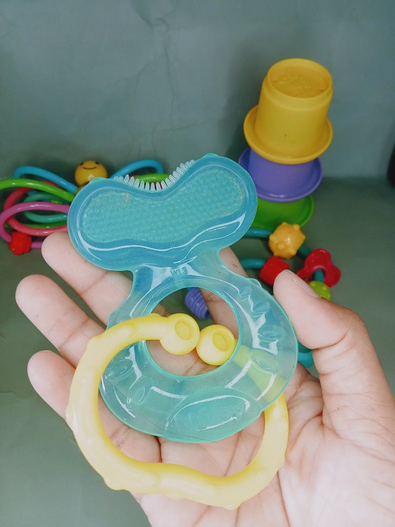 Baby Rattle and Teether Toys Set (Category: Infant Playtime) located in Rosario. Submitted by elysedeclutter (Listing ID 1463382460, Image 2). Description: - Bundle of 4 baby toys - Includes: butterfly rattle, stacking cup set, colorful ring rattle, and blue gel teether - Great for exploration and soothing teething gums - All pieces are colorful and engaging.