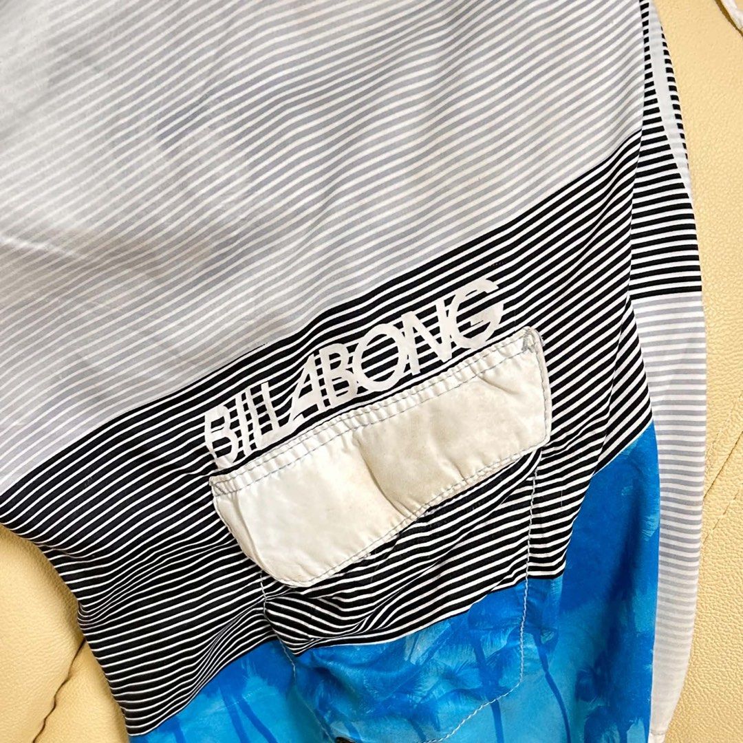 Billabong Board Shorts Size 37 (Category: Swim Trunks & Board Shorts) located in Manila. Submitted by bud_thriftt (Listing ID 1463475648, Image 2). Description: - Billabong Board Shorts - Size: 37 - Design: Cool blue and white stripes with palm tree graphics - Features: Back pocket with velcro closure, drawstring waist for adjustable comfort - Material: 100% Polyester - Ideal for: Swimming, surfing, or lounging by the beach/pool.