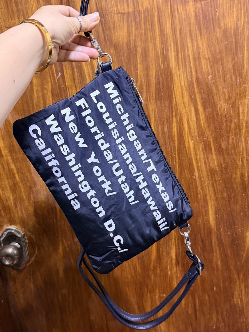 Black Crossbody Bag with US State Names (Category: Cross-body Bags) located in Paete. Submitted by skydruemadison (Listing ID 1463416690, Image 2). Description: - Stylish black crossbody bag with a detachable smaller pouch. - Unique white US state name prints for a touch of wanderlust. - Adjustable strap for comfortable, customized wear. - Secure zipper closure on both the main bag and the pouch. - Made from lightweight material, perfect for all-
