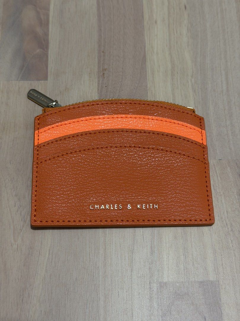 Charles & Keith Orange Cardholder with Zipper (Category: Wallets & Card holders) located in Manila. Submitted by emchi19 (Listing ID 1463530029, Image 1). Description: - Brand: Charles & Keith - Color: Orange - Features: Multiple front card slots - Additional compartment: Zippered pocket for coins or small items - Design detail: Embossed brand name on the front - Overall: Bright and functional.