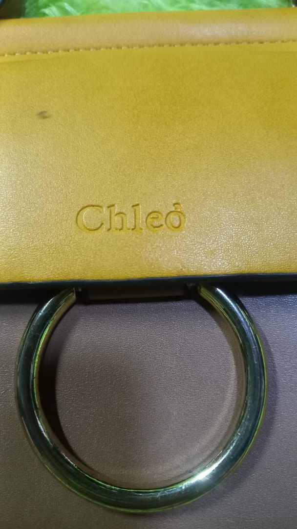 Chleo Small Handbag Shoulder Bag (Category: Luxury Bags & Wallets) located in Manila. Submitted by twinklelyn03 (Listing ID 1463388915, Image 3). Description: - Stylish Chleo handbag - Mix of brown and yellow leather - Elegant gold ring detail on front flap - Vibrant coral-colored interior - Multiple compartments for organization - Includes a long, adjustable strap - Ideal for everyday wear see photos for details pm sa sure buyer only thank you s