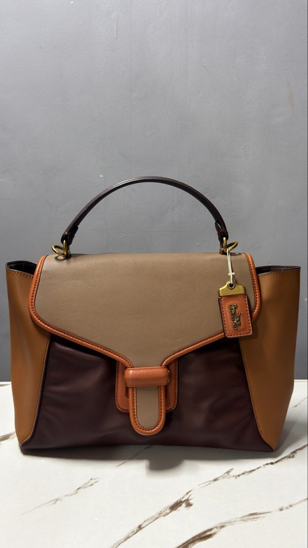 Coach Brown Leather Handbag with Gold Hardware (Category: Luxury Bags & Wallets) located in Manila. Submitted by faye_preloved (Listing ID 1463340342, Image 1). Description: - Classic brown leather handbag - Tan accent details - Gold zipper closure - Gold hardware - Visible interior lining - Versatile for everyday or special occasions - Comes with original packaging inside.