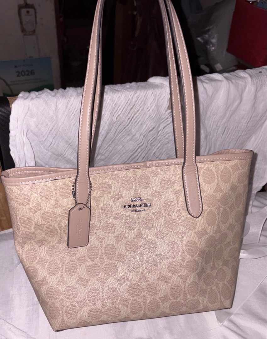 Coach City Tote Bag Beige (Category: Luxury Bags & Wallets) located in Taguig. Submitted by prelovedbydein (Listing ID 1463501384, Image 1). Description: - NGA Coach tote bag (u need to legit check if maselan) - Signature beige print with tan leather trim and handles - Interior zip pocket and slip pockets - Includes Coach hangtag - Ideal for everyday use.