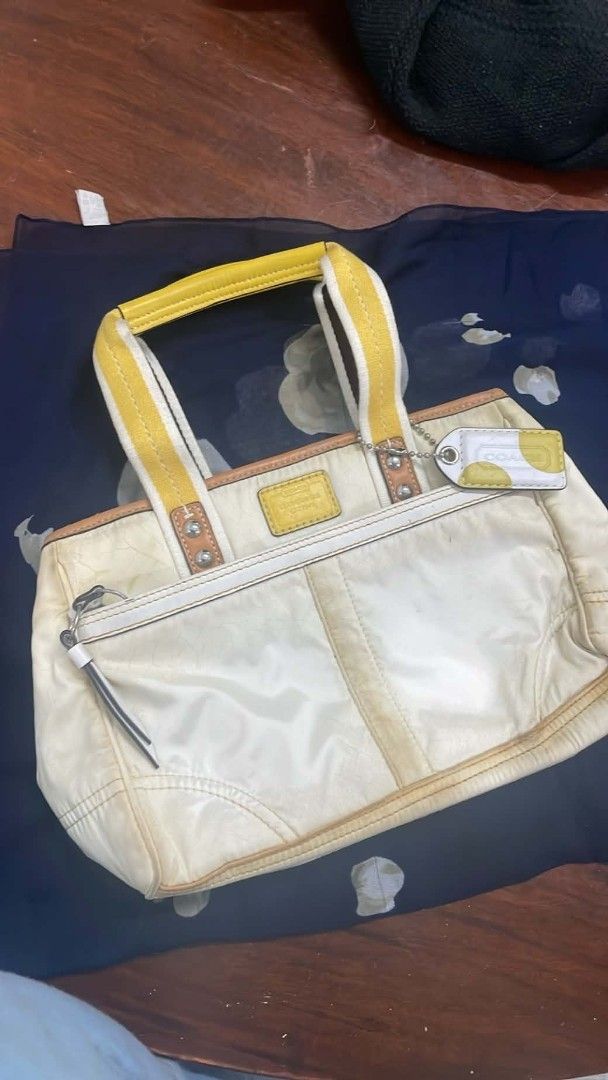 Coach Hampton Nylon Sateen Weekend Tote Handbag. (Category: Luxury Bags & Wallets) located in Caloocan City. Submitted by elle_f08 (Listing ID 1463340615, Image 1). Description: - Cream-colored Coach tote bag - Yellow and white striped handles - Front zip pocket - Small side zip pocket - Coach hang tag with yellow polka dots - Signs of wear and discoloration on exterior (bottom and handles) - Still functional and stylish.