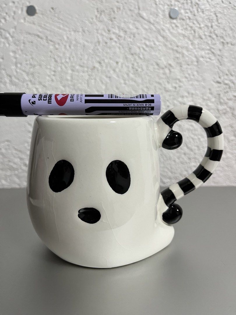 Cute Ghost Mug with Striped Handle (Category: Coffee & Tea Tableware) located in Mandaue City. Submitted by allthingzdopamine (Listing ID 1463373176, Image 2). Description: -White ghost mug with black eyes and mouth -Black and white striped handle -Features fine surface cracks -Perfect for Halloween or spooky enthusiasts -Great for your daily coffee or tea -has visible crazings at the back of the mug, but none on the inside .