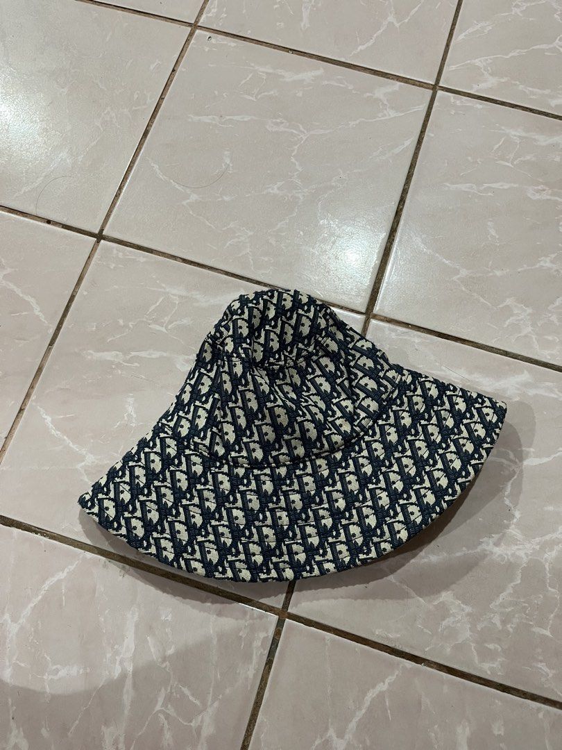 Dior Oblique Bucket Hat (Category: Hats & Beanies) located in Tabuk. Submitted by collectors_thrift_shop (Listing ID 1463328072, Image 2). Description: - Classic Dior bucket hat - Features iconic Dior Oblique pattern - Dark blue and beige colorway - Ideal for sunny days - Essential fashion accessory.