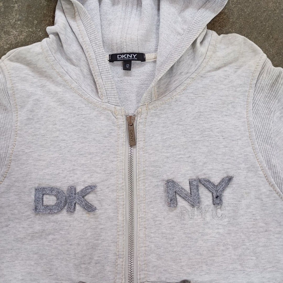 DKNY Grey Zip-Up Hoodie (Category: Coats, Jackets and Outerwear) located in Calamba. Submitted by doityourselfffff (Listing ID 1463547510, Image 2). Description: - Grey DKNY zip-up hoodie - DKNY logo on chest - Two front pockets with button details - Ruffled hemline - Made in China - Size 12 18 x 23 measurements excellent condition used.