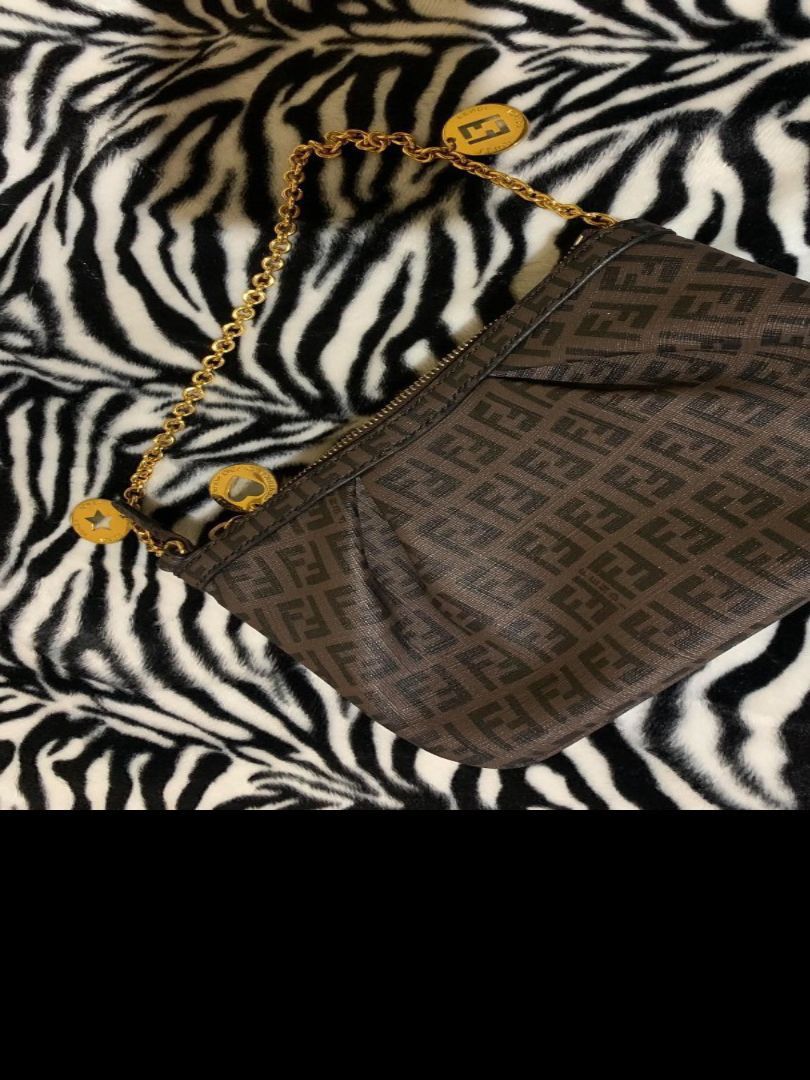 Fendi Zucca Monogram Pouch Bag (Category: Luxury Bags & Wallets) located in Gapan. Submitted by cleverstar.36492b (Listing ID 1463339021, Image 1). Description: Authentic Fendi pouch bag. Features the classic Zucca monogram pattern. Gold chain strap with charm details. Made in Italy. Interior has a Fendi leather tag and authenticity sticker. Zipper closure..