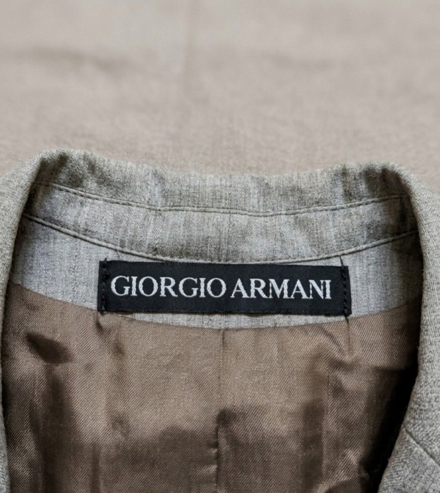 GIORGIO ARMANI LE COLLEZIONI blazer (Category: Coats, Jackets and Outerwear) located in Baguio. Submitted by luxeloomarchive (Listing ID 1463501146, Image 3). Description: This is a grey pinstripe suit jacket labeled "GIORGIO ARMANI LE COLLEZIONI". It has a vertical-line texture, a chest pocket, two front flap pockets, and three buttons. It appears to be vintage. ​Key product specifications: ​Size: 48 (EU/IT) ​Material: 55% wool, 25% polyester, 2