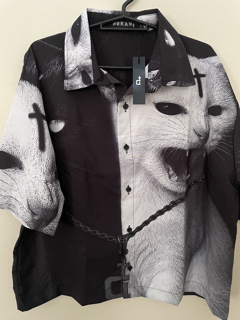 DGRAVE Polo Shirt (Category: Tshirts & Polo Shirts ) located in Manila. Submitted by kristinamaria (Listing ID 1463340313, Image 1). Description: - Unique black and white graphic shirt - Features a cat and cross design - Short sleeves - Button-up front - All-over print - Estimated size Medium/Large (check measurements for best fit) - Perfect statement piece.