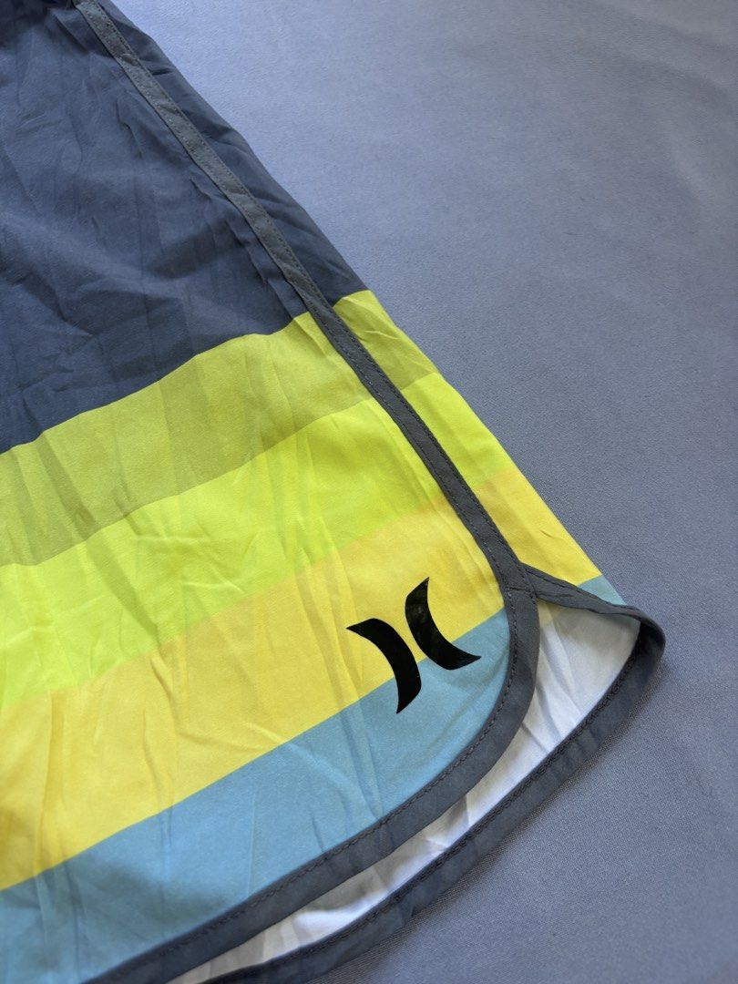 Hurley Phantom Board Shorts Size 32 Striped (Category: Swim Trunks & Board Shorts) located in Manila. Submitted by galitsabarat (Listing ID 1463408382, Image 3). Description: - Hurley Phantom Board Shorts - Size: 32 - Color: Grey, yellow, and blue stripe pattern - Features: Drawstring waist, velcro fly, one back pocket with zip closure - Ideal for: Swimming, lounging, beach, or pool activities.
