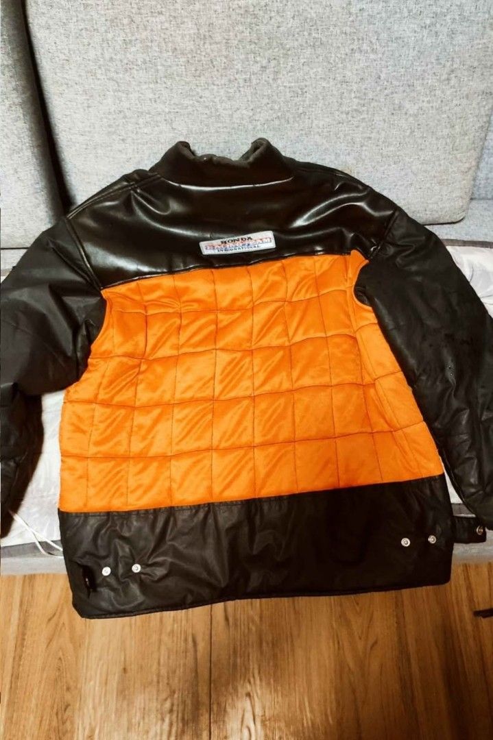 HW Racing Team Jacket - Orange & Black (Category: Coats, Jackets and Outerwear) located in Manila. Submitted by pogascar (Listing ID 1463339324, Image 2). Description: - Eye-catching racing jacket - Vibrant orange quilted front - Sleek black faux leather sleeves and collar - Adorned with multiple iconic motorsport patches: Elf Moto, Camel, Honda, Think Fast, MSD Ignition, Tag Heuer, Ferrari, Ainimoto - Secure zipper closure - Estimated size: Larg