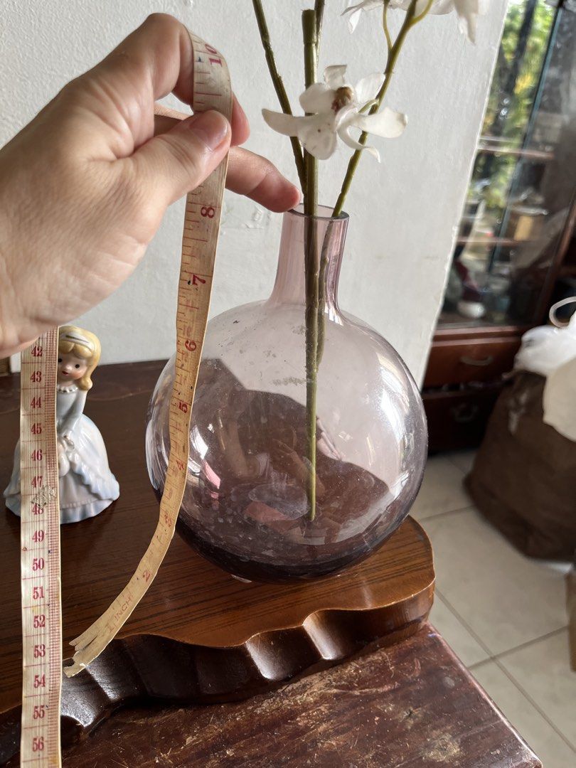 Ikea hand blown Glass Vase (Category: Vases & Decorative Bowls) located in Taguig. Submitted by minmin_parker (Listing ID 1463430507, Image 3). Description: - Elegant 8-inch tall round glass vase with a subtle purple hue. - Comes with realistic artificial white orchid stems. - Includes a charming small porcelain doll figurine. - Ideal for enhancing shelf or table decor. - Makes a thoughtful gift for any occasion..