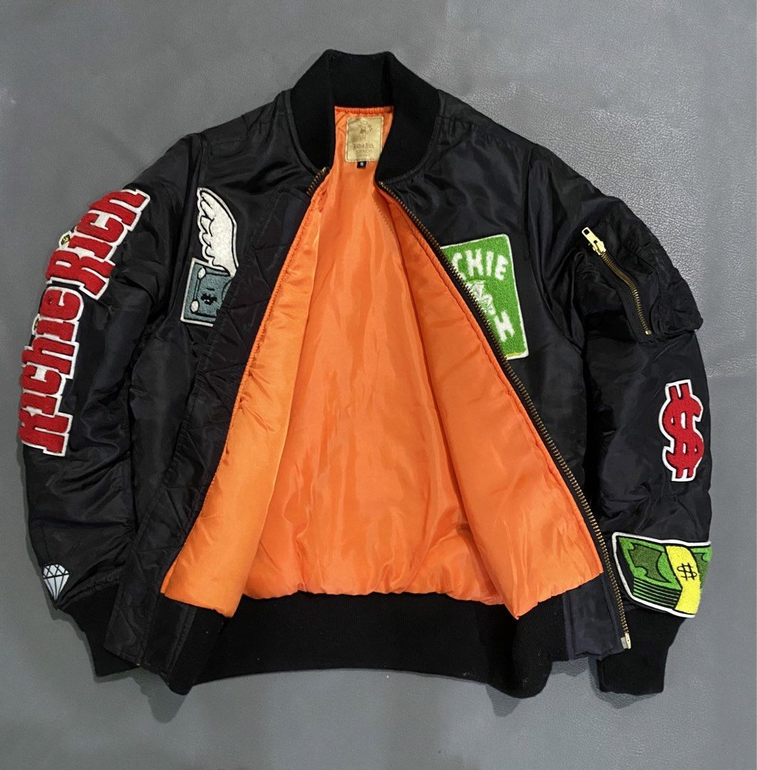 Joyrich x Richie Rich Bomber Jacket (Category: Coats, Jackets and Outerwear) located in Pozorrubio. Submitted by izaykite2g (Listing ID 1463383704, Image 2). Description: - Brand: Joyrich - Style: Black Bomber Jacket - Size: S - 20 inches wifth - 25.5 inches length - Details: 'Richie Rich' text on sleeves, Monopoly Man patch, dollar sign patches - Lining: Bright orange - Zipper: YKK.
