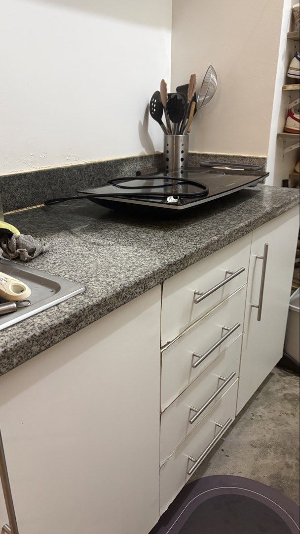 Kitchen Base Cabinets and countertop and backsplash granite (Category: Cookers) located in Mandaluyong City. Submitted by anjie52 (Listing ID 1463368725, Image 1). Description: 180cm L x 60cm W White kitchen base cabinets * Modern, flat-front design * 4 stacked drawers on the left * 1 single-door cabinet on the right * Long horizontal brushed-metal handles * Dark gray/black speckled granite countertop * Matching raised granite backsplash * Standa