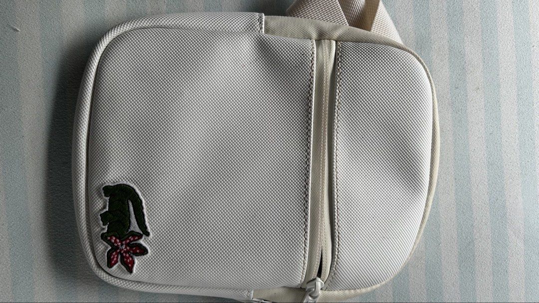 Lacoste x Stranger Things Crossbody Bag White (Category: Cross-body Bags) located in Bulacan. Submitted by peachyaguilar (Listing ID 1463381168, Image 1). Description: - White Lacoste crossbody bag - Features a Stranger Things graphic on the front pocket - Zipper closure - Adjustable strap - Ideal for everyday use or travel - Small and compact design.