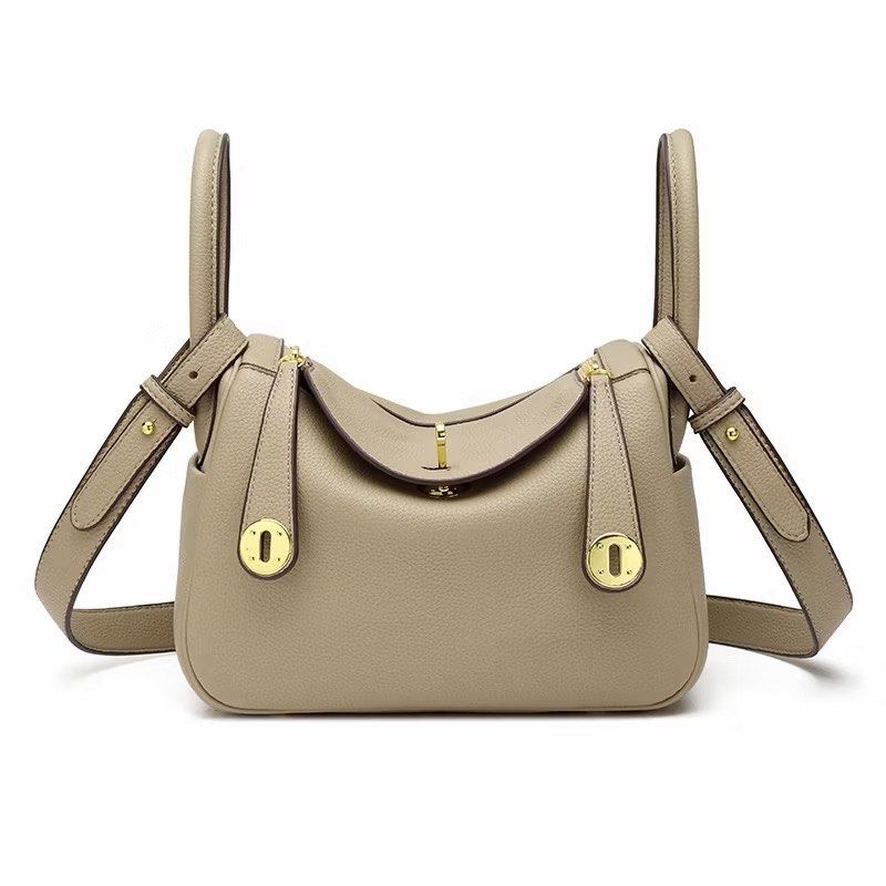 LINDY Designer Inspired Leather Handbag (Category: Cross-body Bags) located in Cavite. Submitted by lovedbypriley (Listing ID 1463346485, Image 1). Description: - Taupe leather handbag - Elegant gold hardware - Comfortable top handles - Detachable shoulder strap for versatility - Secure zipper closure - Stylish front lock detail - Spacious interior for all your essentials - Perfect for everyday chic or special events - Exudes sophistication.