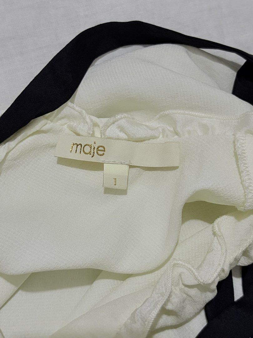 Maje White Ruffle Bow Top (Category: Blouses) located in General Mariano Alvarez. Submitted by b3yaaa (Listing ID 1463454214, Image 2). Description: - Features: Ruffled neckline with black ribbon tie - Size: 1 - Versatility: Perfect for dressing up or down.