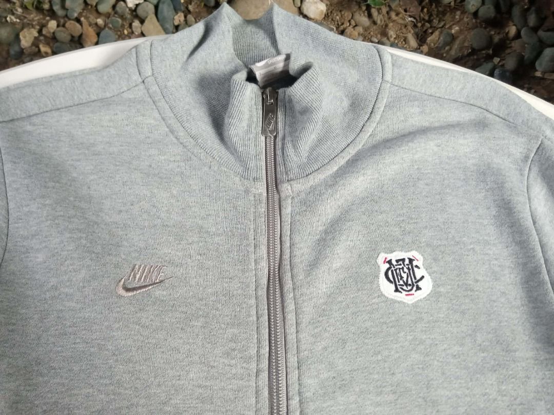 Nike Grey Track Jacket with Crest Logo (Category: Coats, Jackets and Outerwear) located in Pasig City. Submitted by rjkfindsofficial (Listing ID 1463405490, Image 2). Description: - Grey Nike track jacket - Size: L - Dimes L27 x W20 - Features a small embroidered crest logo on the chest - Full zip closure - Includes pockets - Made in China - Ideal for casual wear or sports activities - All zipper working - Complete tags - Minimal stain - Ribbings