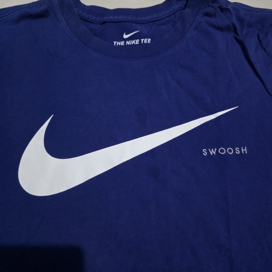 Nike Swoosh T-shirt Blue (Category: Tshirts & Polo Shirts ) located in Quezon City. Submitted by kick_mnl (Listing ID 1463374743, Image 2). Description: - Blue Nike T-Shirt - Large white Swoosh logo with vertical 'SWOOSH' text - 'THE NIKE TEE' printed on the inside collar - Approximate Measurements: 24" chest, 17" shoulder to hem - Ideal for casual everyday wear.