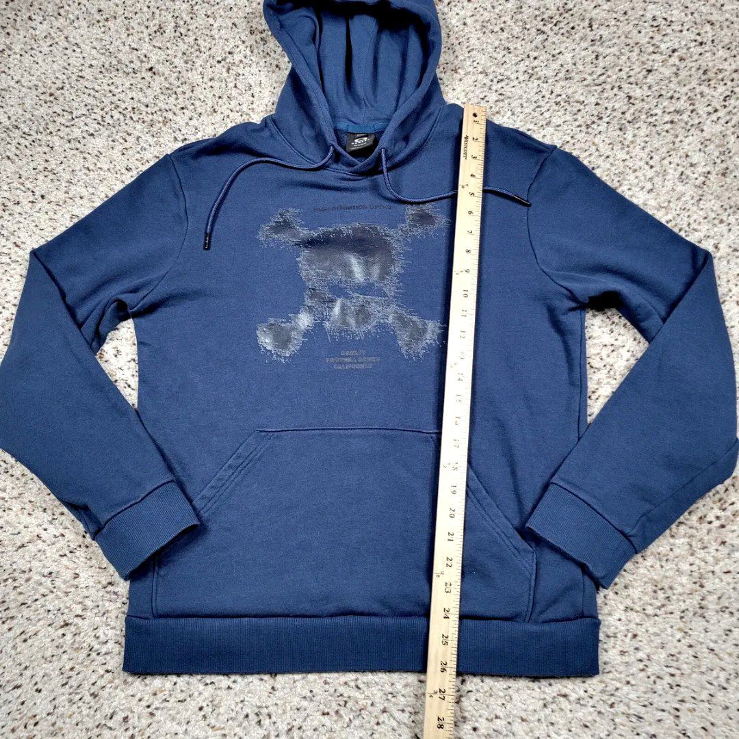 Oakley Hoodie Jacket (Category: Coats, Jackets and Outerwear) located in Manila. Submitted by icamalicdem29 (Listing ID 1463150322, Image 3). Description: teal-blue pullover hoodie featuring a distressed graphic skull and text logo detail on the chest, along with a front kangaroo pocket.