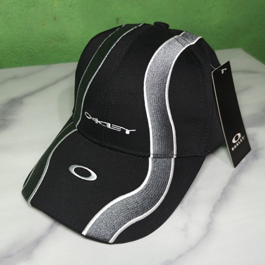 Oakley Wave Cap (High Quality Replica) (Category: Caps & Hats) located in Dasmarinas. Submitted by nifty_n00k (Listing ID 1463328351, Image 1). Description: - Brand: Oakley - Color: Black - Design: Silver wave-like stripes on front and sides - Embellishments: Embroidered Oakley logo on front, 'Oakley' text on side - Condition: Brand new with original tag attached - Style: Ideal for casual wear.