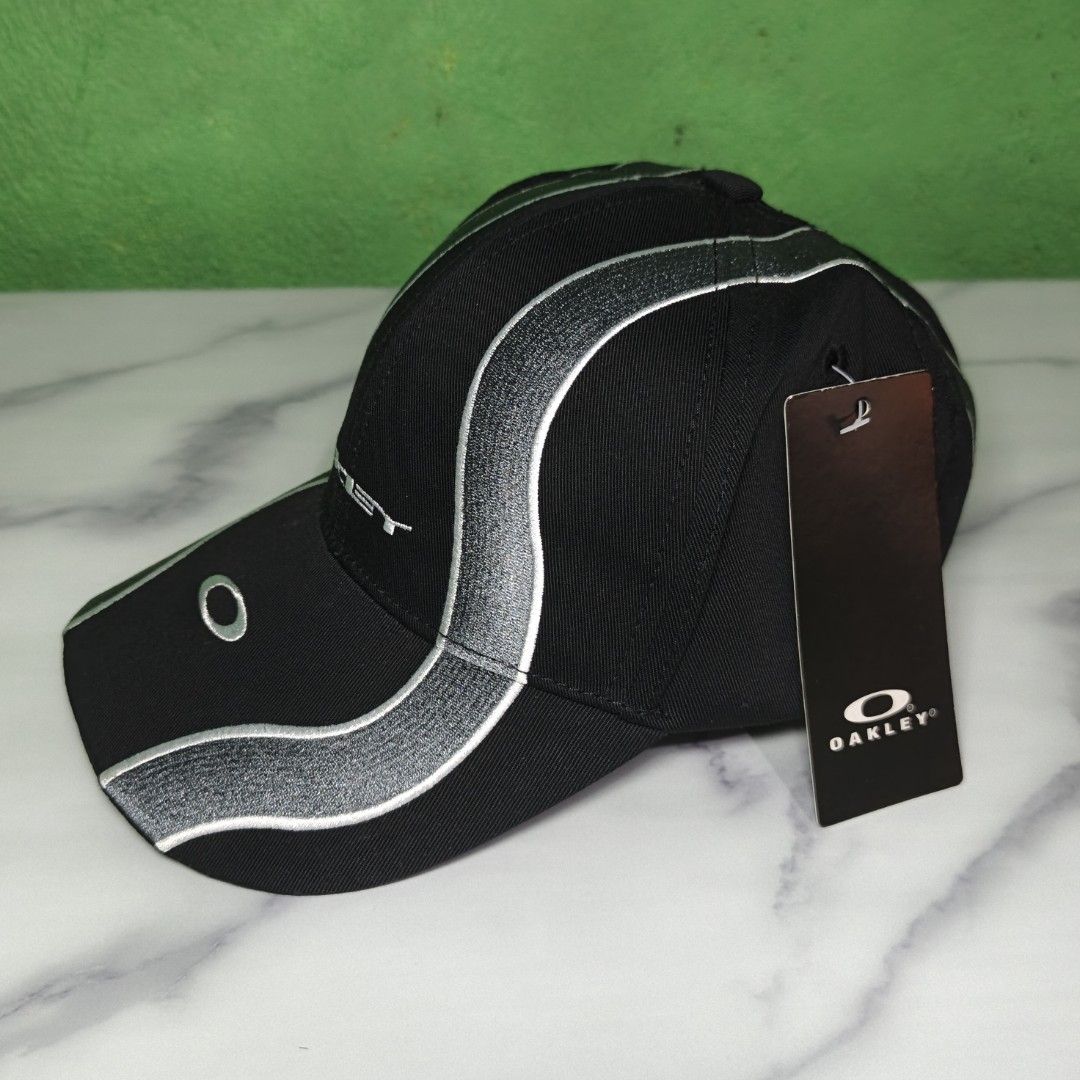 Oakley Wave Cap (High Quality Replica) (Category: Caps & Hats) located in Dasmarinas. Submitted by nifty_n00k (Listing ID 1463328351, Image 3). Description: - Brand: Oakley - Color: Black - Design: Silver wave-like stripes on front and sides - Embellishments: Embroidered Oakley logo on front, 'Oakley' text on side - Condition: Brand new with original tag attached - Style: Ideal for casual wear.
