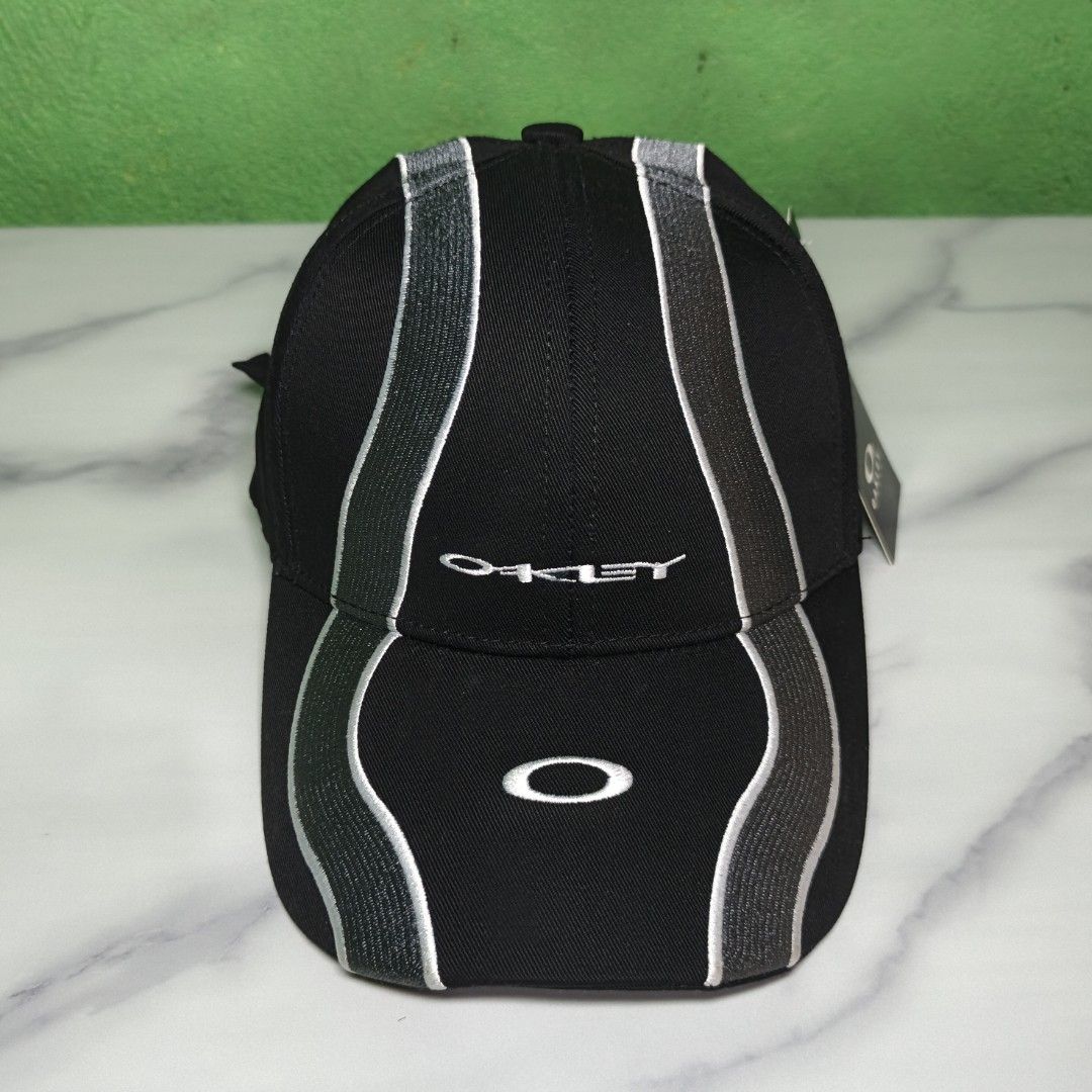 Oakley Wave Cap (High Quality Replica) (Category: Caps & Hats) located in Dasmarinas. Submitted by nifty_n00k (Listing ID 1463328351, Image 2). Description: - Brand: Oakley - Color: Black - Design: Silver wave-like stripes on front and sides - Embellishments: Embroidered Oakley logo on front, 'Oakley' text on side - Condition: Brand new with original tag attached - Style: Ideal for casual wear.
