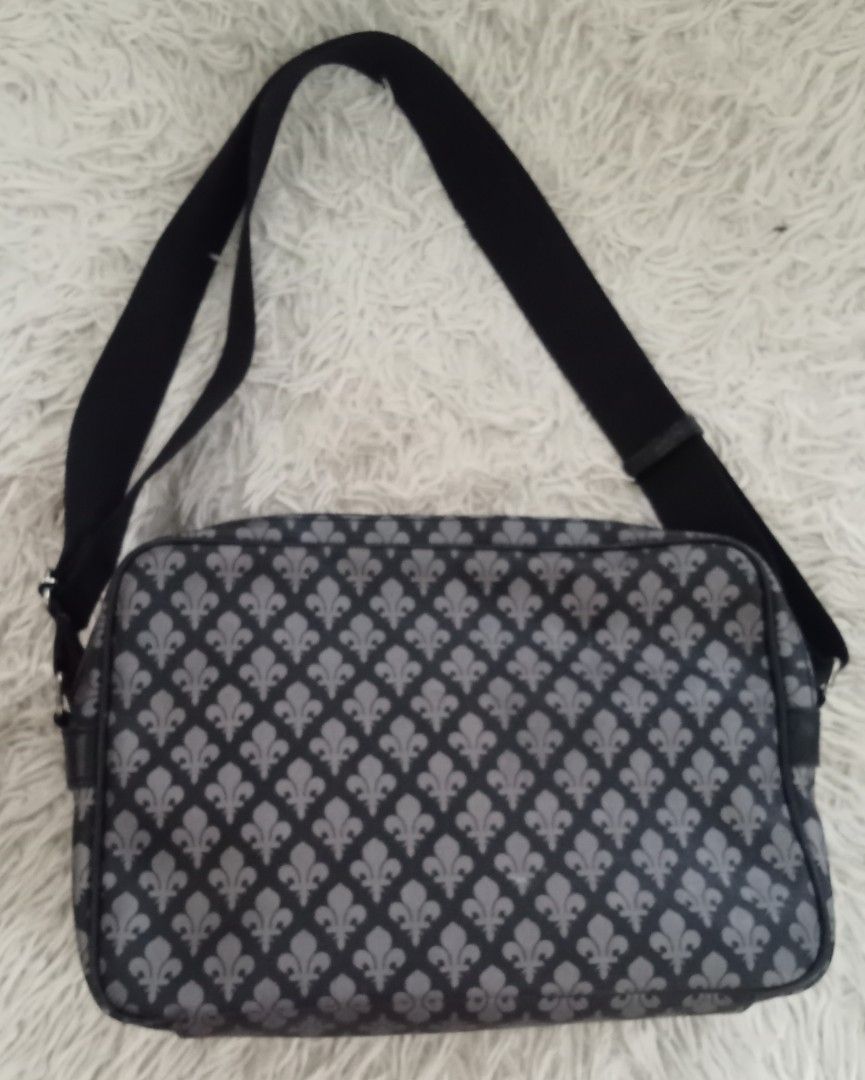 Patrick Cox Black & Grey Fleur-de-lis Crossbody Bag (Category: Cross-body Bags) located in Caloocan City. Submitted by noy5o1a (Listing ID 1463364774, Image 2). Description: - Stylish black and grey crossbody bag - Features a repeating fleur-de-lis pattern - Multiple zippered compartments for easy organization - Adjustable strap for comfortable wear - Ideal for everyday use or travel.