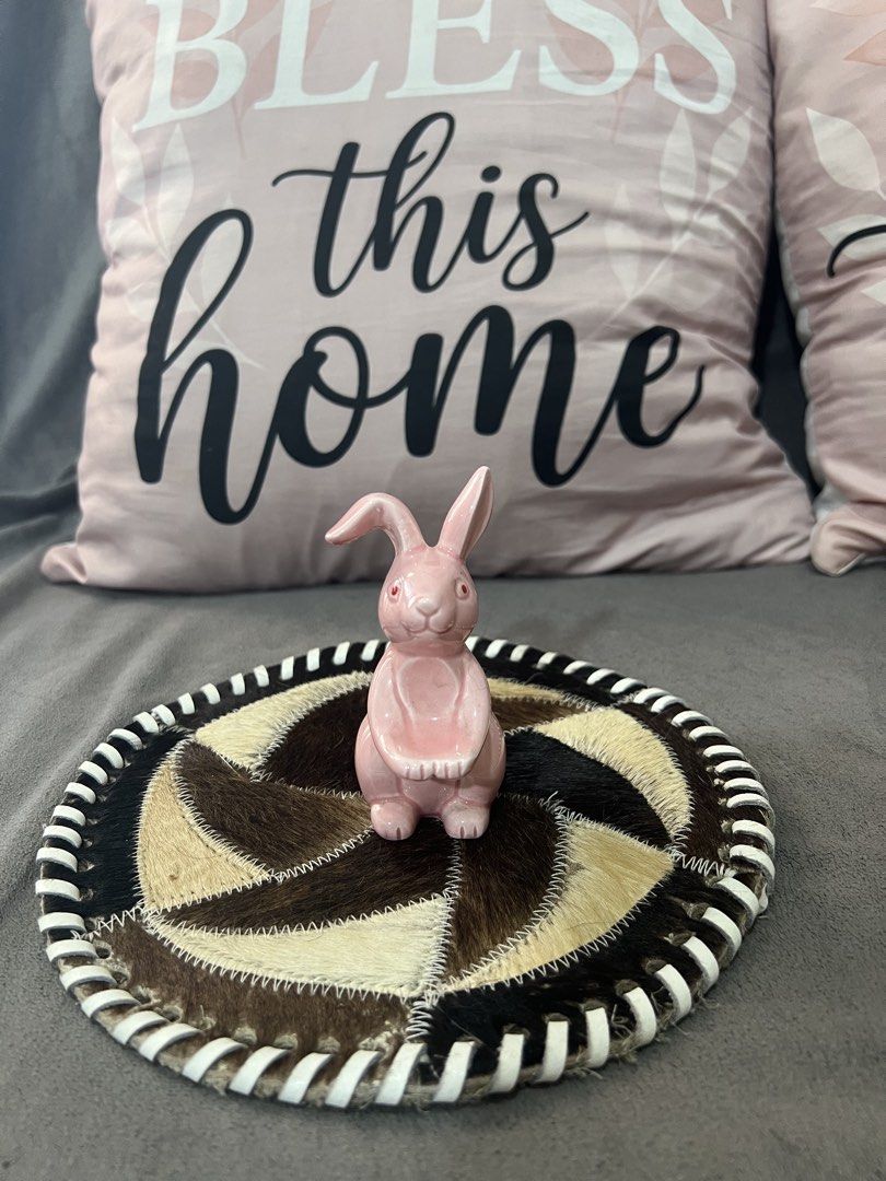 Pink Ceramic Bunny Figurine on Decorative Coaster (Category: Other Home Decor) located in Las Pinas. Submitted by maple0305 (Listing ID 1463347350, Image 1). Description: - Cute pink ceramic bunny figurine - Sits on a unique round coaster made of patchwork animal hide - Striped trim on the coaster adds a stylish detail - Ideal for Easter decorations or as a charming shelf accent - Brings a whimsical touch to any room - Approximately 4 inches in h