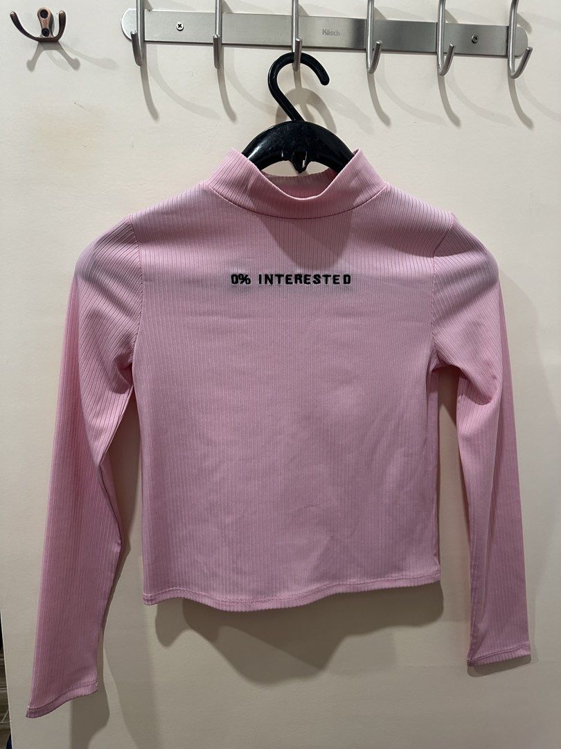 Pink Ribbed Mock Neck Top (Category: Blouses) located in Davao. Submitted by secondlife.authentic (Listing ID 1463462824, Image 1). Description: - Pink ribbed long-sleeved top - Mock neck design - Features "0% INTERESTED" text on the front - Cropped style - Ideal for casual, statement looks - Versatile: pairs well with jeans or skirts.