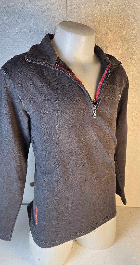 Prada Grey 1/4 Zip Sweatshirt (Category: Longsleeves) located in Pasig City. Submitted by dertah (Listing ID 1463434171, Image 3). Description: - Authentic Prada grey long-sleeved sweatshirt - Features a 1/4 zip closure with striking red lining - Subtle Prada logo elegantly embroidered on the chest - Small, iconic red Prada tag detail on the side - Ideal for a stylish and comfortable casual look -100% Authentic -100% Japan - Super Value for money