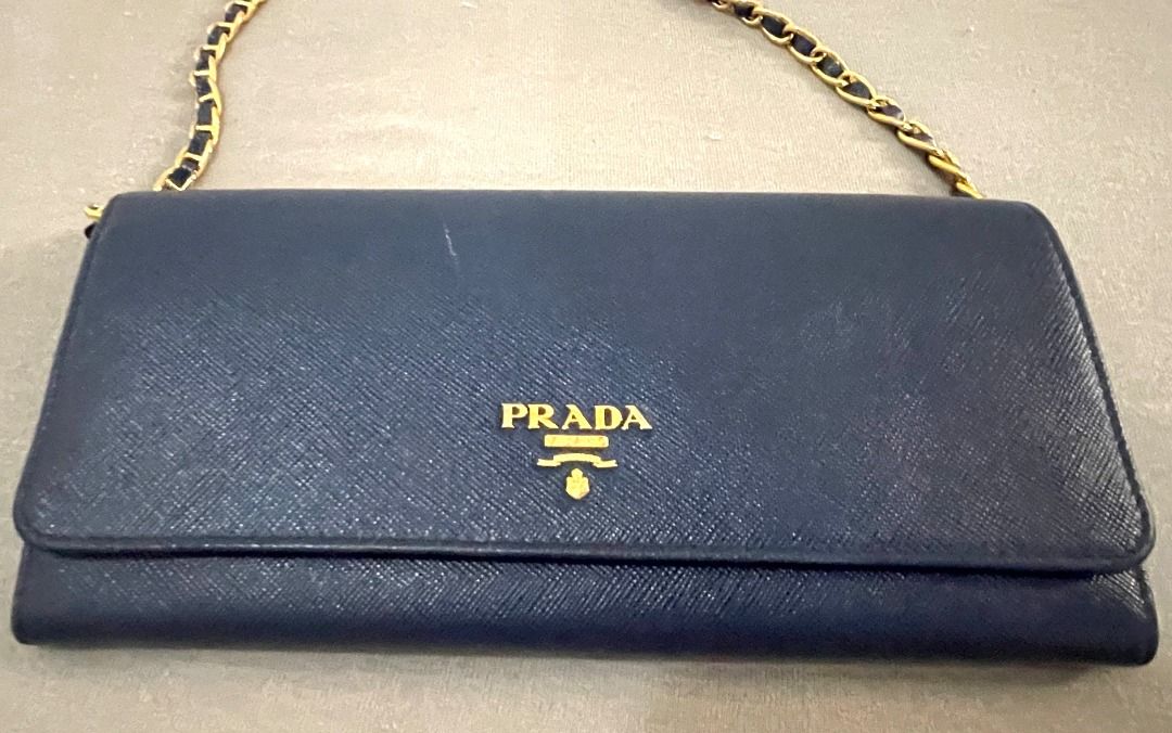 Prada Saffiano Leather Wallet on Chain Navy Blue (Category: Luxury Bags & Wallets) located in General Tinio. Submitted by the_bargainhunter (Listing ID 1463341856, Image 2). Description: - Navy blue Prada Saffiano leather wallet on chain - Gold hardware - Detachable chain strap for versatile wear (clutch or crossbody) - Interior features card slots and a zip pocket - Sold as is.