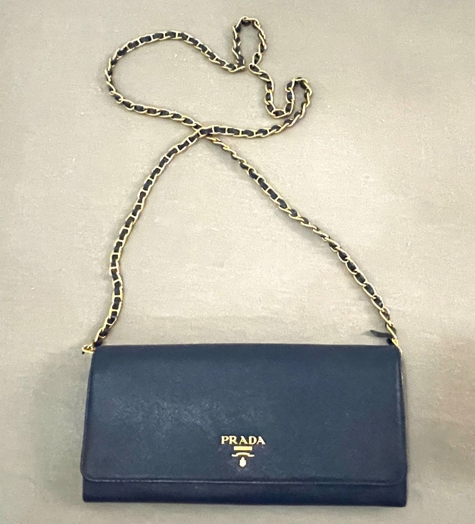 Prada Saffiano Leather Wallet on Chain Navy Blue (Category: Luxury Bags & Wallets) located in General Tinio. Submitted by the_bargainhunter (Listing ID 1463341856, Image 1). Description: - Navy blue Prada Saffiano leather wallet on chain - Gold hardware - Detachable chain strap for versatile wear (clutch or crossbody) - Interior features card slots and a zip pocket - Sold as is.