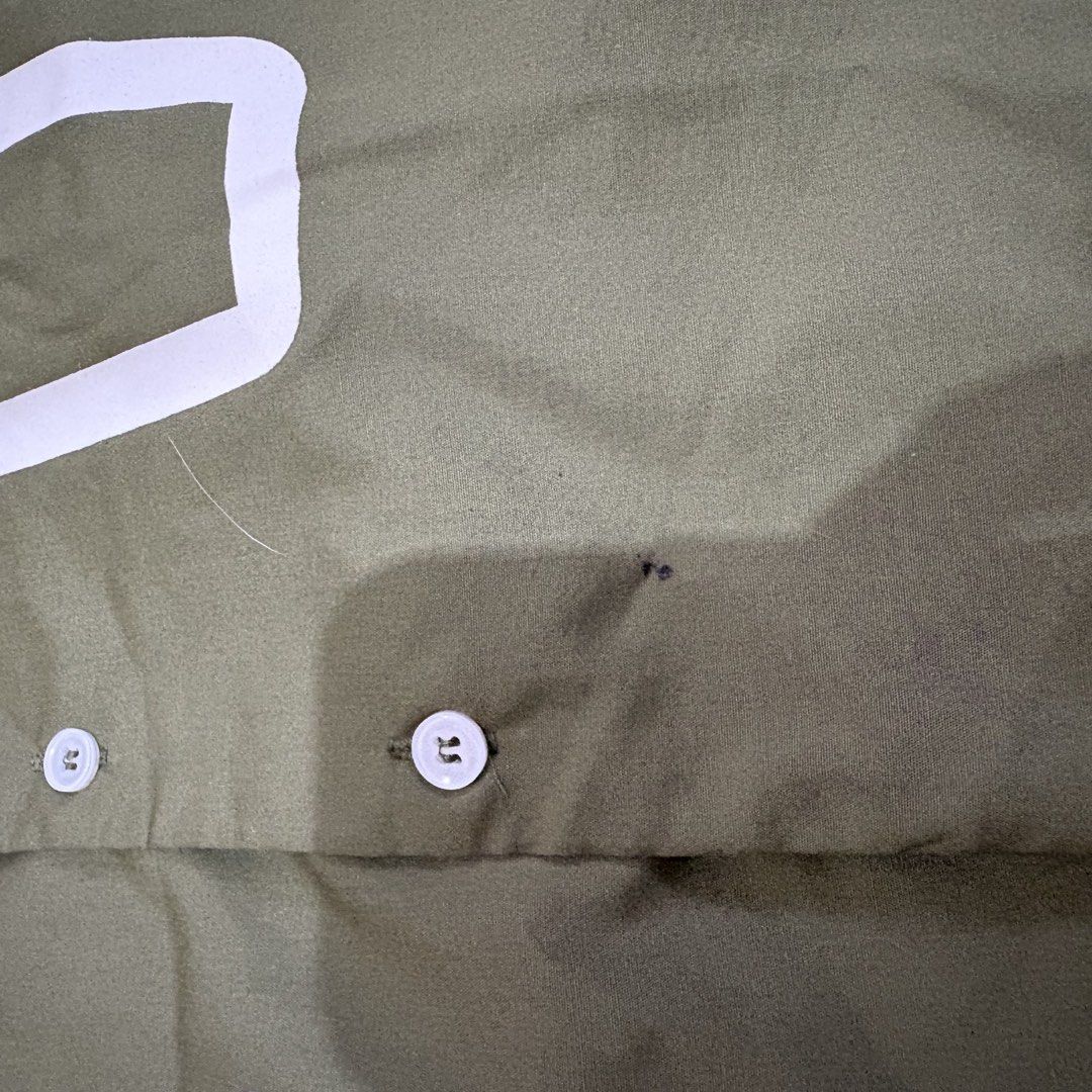 SMYTH Buttondown (Category: Tshirts & Polo Shirts ) located in Makati City. Submitted by sseurekiii (Listing ID 1463348269, Image 2). Description: - Olive green shirt - White graphic detail on front - Two white buttons - Minor dark marks on fabric - Stray white thread - Perfect for casual wear - Used once - Issue: tiny pinhole on the bottom part (nasabugan ng fireworks last NYE 💀) see 2nd photo.