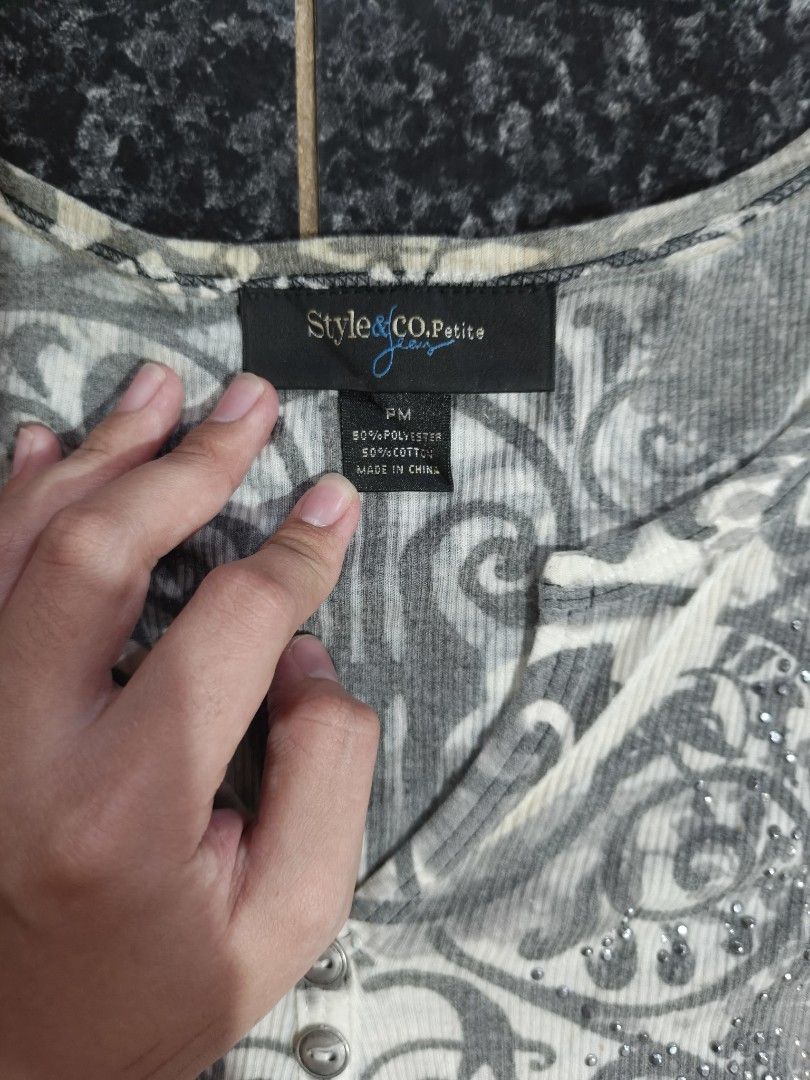 Style & Co Petite Women's Top (Category: Sleeveless) located in Manila. Submitted by sunnysideup.tree (Listing ID 1463384357, Image 3). Description: - Style & Co Petite top - Grey and white ornate floral print with subtle sparkle - Ribbed texture - Henley neckline with three buttons - Elbow-length sleeves - Ideal for casual wear.