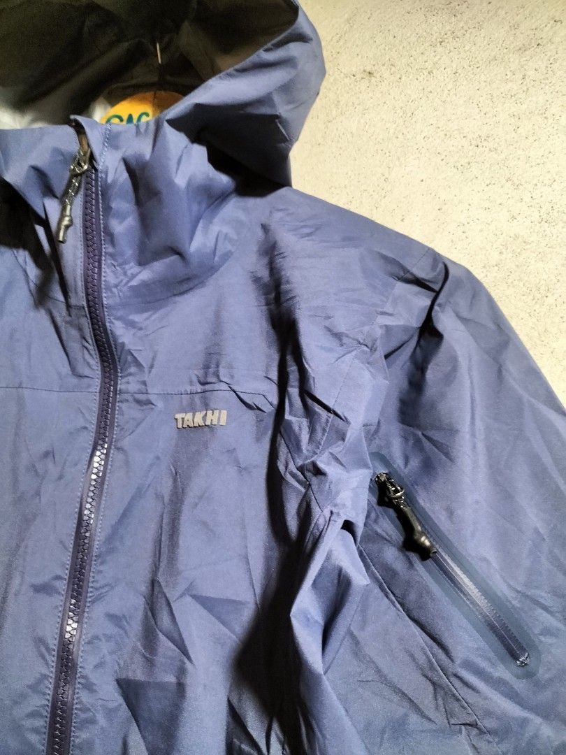 TAKHI Blue Hooded Waterproof Jacket (Category: Coats, Jackets and Outerwear) located in Valencia. Submitted by cabisaythriftshop (Listing ID 1463416782, Image 2). Description: - TAKHI blue hooded jacket - Size 85 - Waterproof/windbreaker style - Zippered pockets (front and sides) - Grey inner lining - Ideal for outdoor activities and everyday wear.