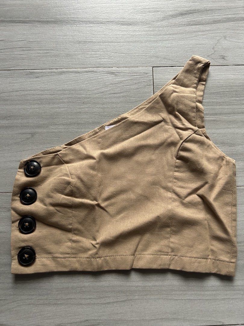 Tan One Shoulder Crop Top with Button Detail (Category: Sleeveless) located in Bacolod City. Submitted by bacolodprelovedstuffs (Listing ID 1463375003, Image 1). Description: - Tan one-shoulder crop top - Features three dark buttons on the side - Versatile: pairs well with skirts or high-waisted pants - Comfortable and stylish for casual outings or nights out - please see more photos for WW.
