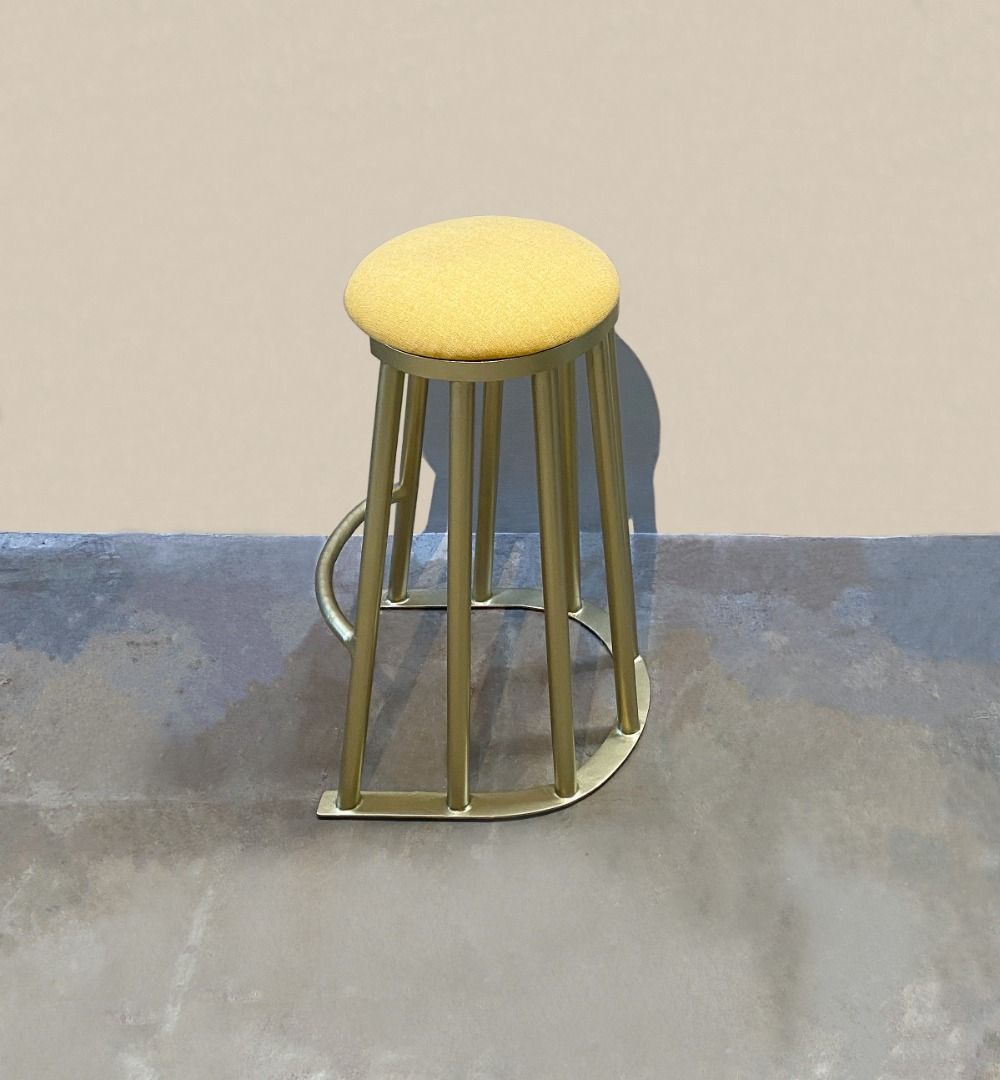 Tanzan Counter Stool (Category: Chairs) located in Paranaque City. Submitted by furniturepiecesph (Listing ID 1463369580, Image 3). Description: This Tanzan Counter Stool, balances a minimalist silhouette with striking sculptural textures. Features a thick, rounded yellow cushion covered in a textured fabric, ensuring a comfortable sit. Cage-Like Base: Built from curved gold-finished metal rods that form a rhythmic vertical cage pattern, resting 