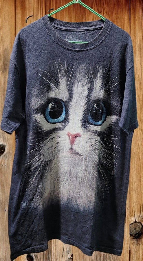 The Mountain Cat Face T-Shirt (Category: Tshirts & Polo Shirts ) located in Camiling. Submitted by sundot_kalikot (Listing ID 1463454218, Image 1). Description: - Realistic cat face graphic t-shirt - Features big blue eyes and fluffy fur detail - Brand: The Mountain - Estimated size: Small - Ideal for cat lovers - Great for casual wear.