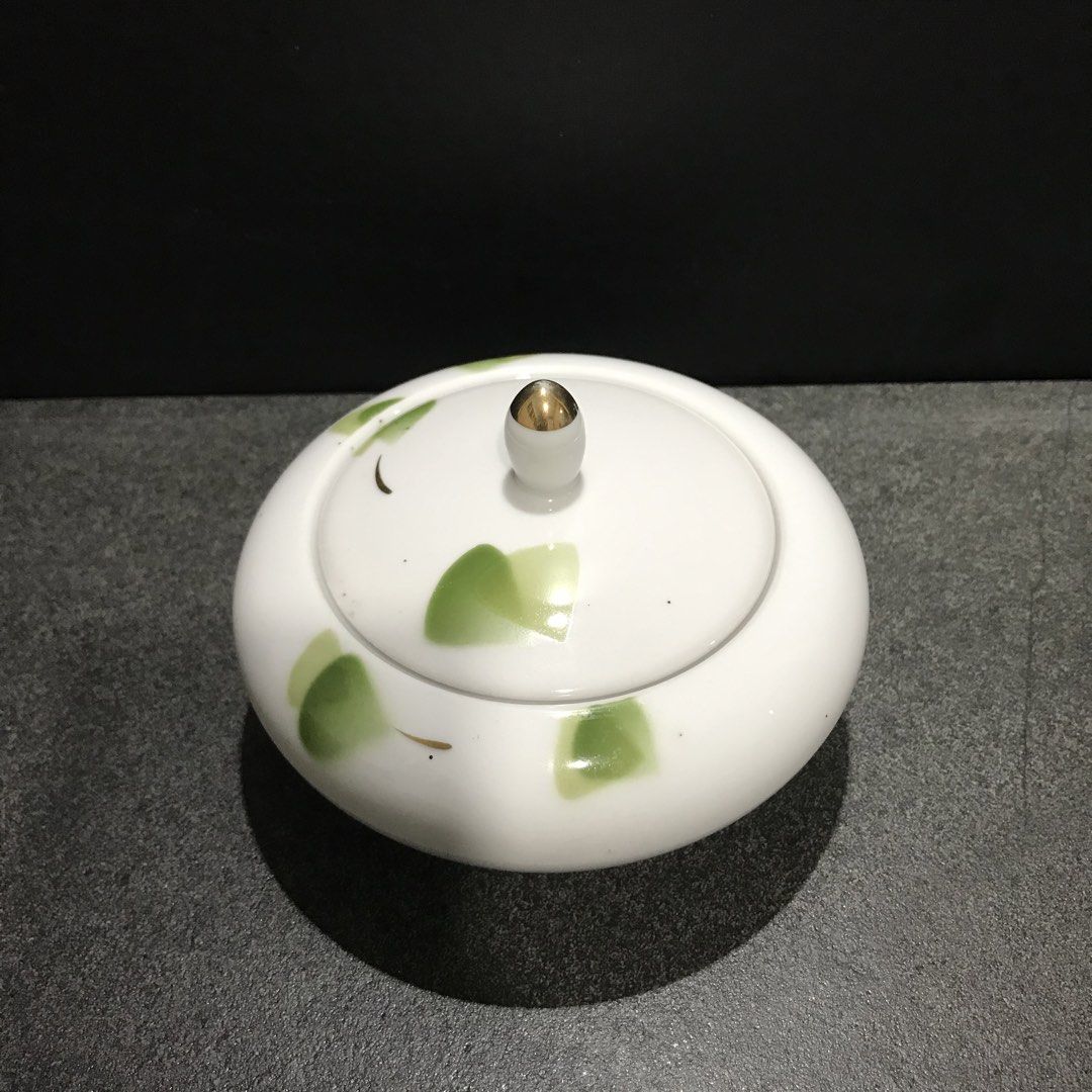 White Ceramic Sugar Bowl with Green Leaf Design (Category: Dinnerware & Cutlery) located in Baao. Submitted by all.things.japan (Listing ID 1463550755, Image 2). Description: 3.5 x 5.25 (w) inches - White ceramic sugar bowl with lid - Features a delicate green leaf pattern - Gold accent on the lid knob - Clean white interior - Maker's mark on the bottom - Ideal for serving sugar or as a decorative accent.